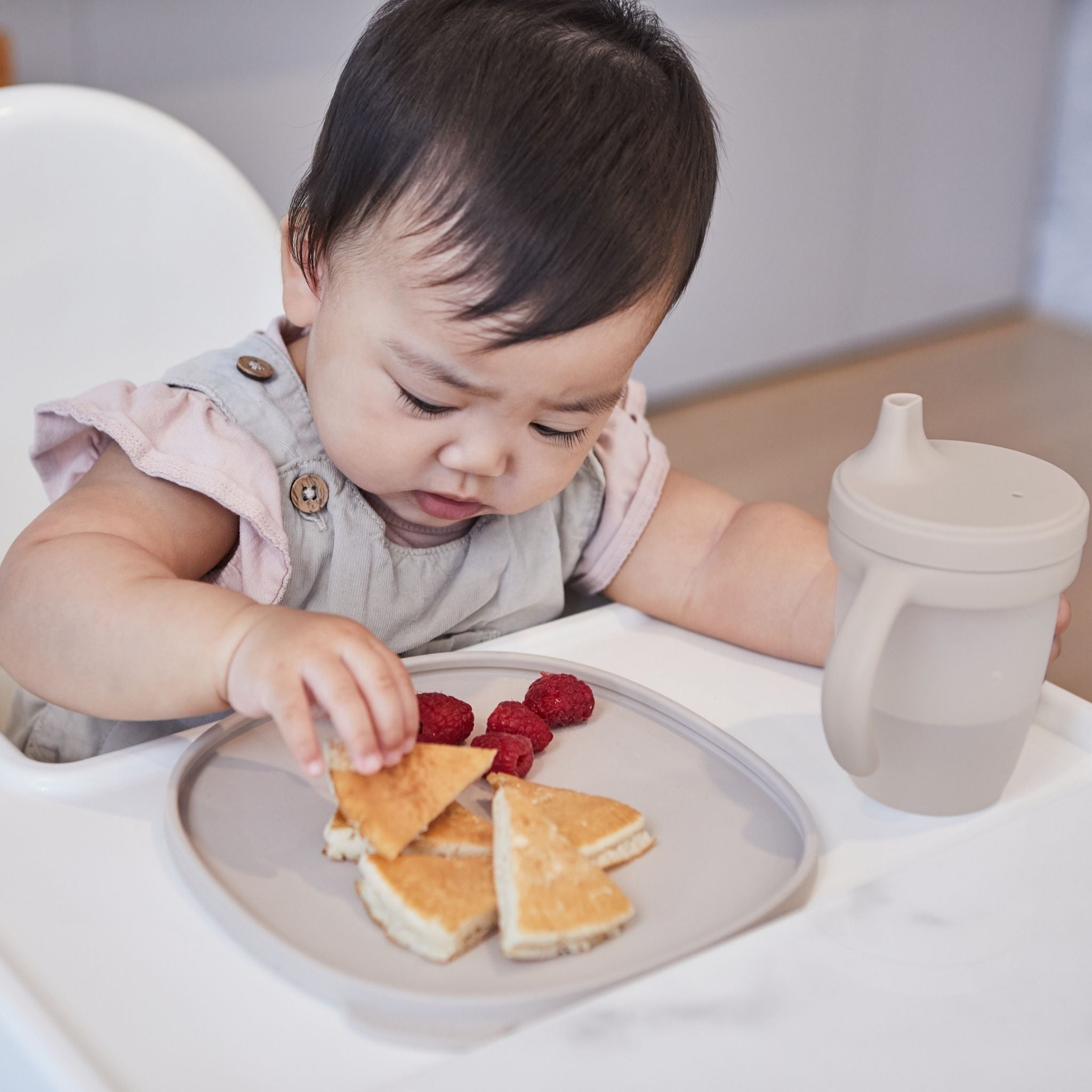 ハンドル付きシリコンスパウトカップlatteカラーとプレートを使う女の子