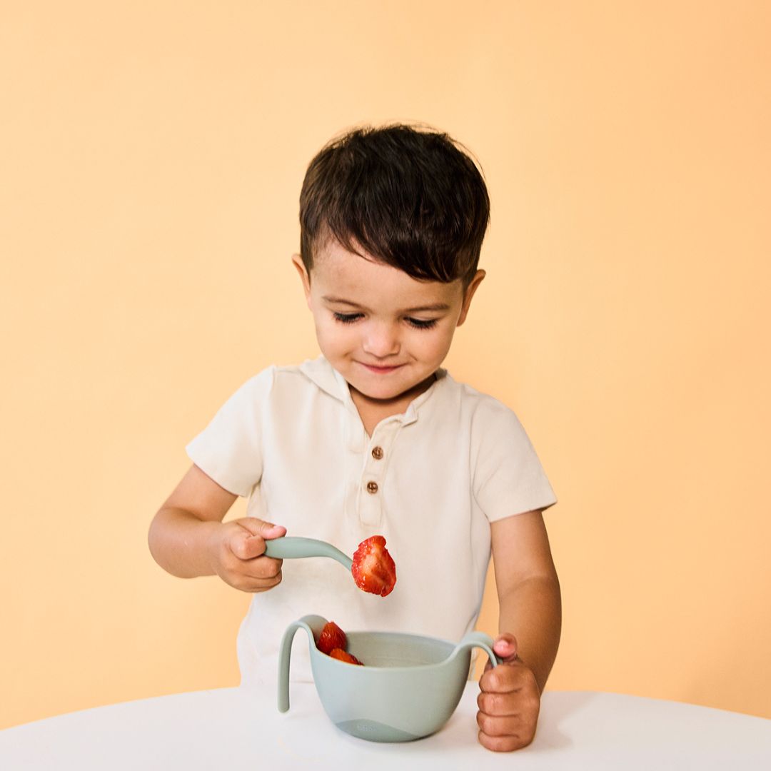 ビーボックスのシップスナックボウルを左手に持ってカトラリーを使ってイチゴを食べている男の子