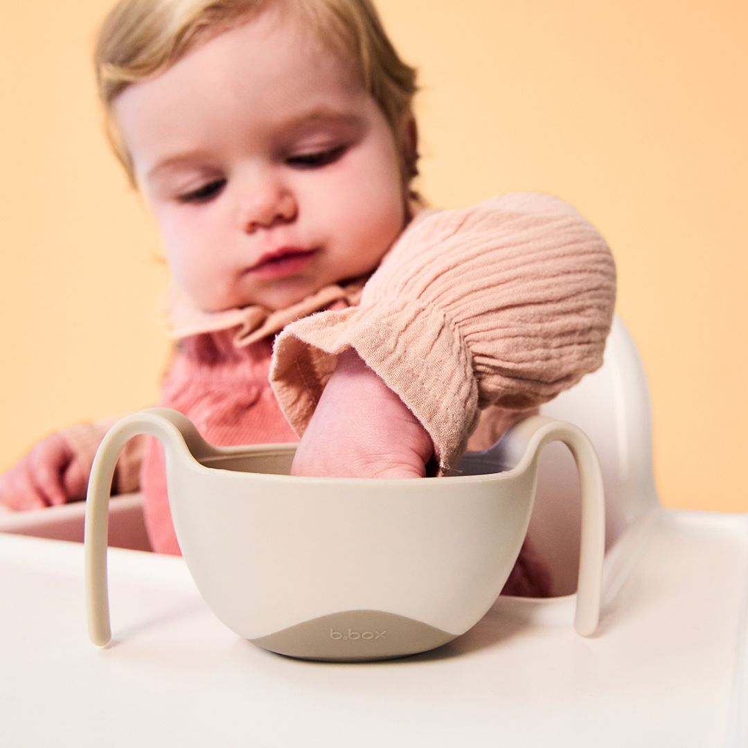 お食事ボウルにてを入れて食べ物を掴んでいる女の子