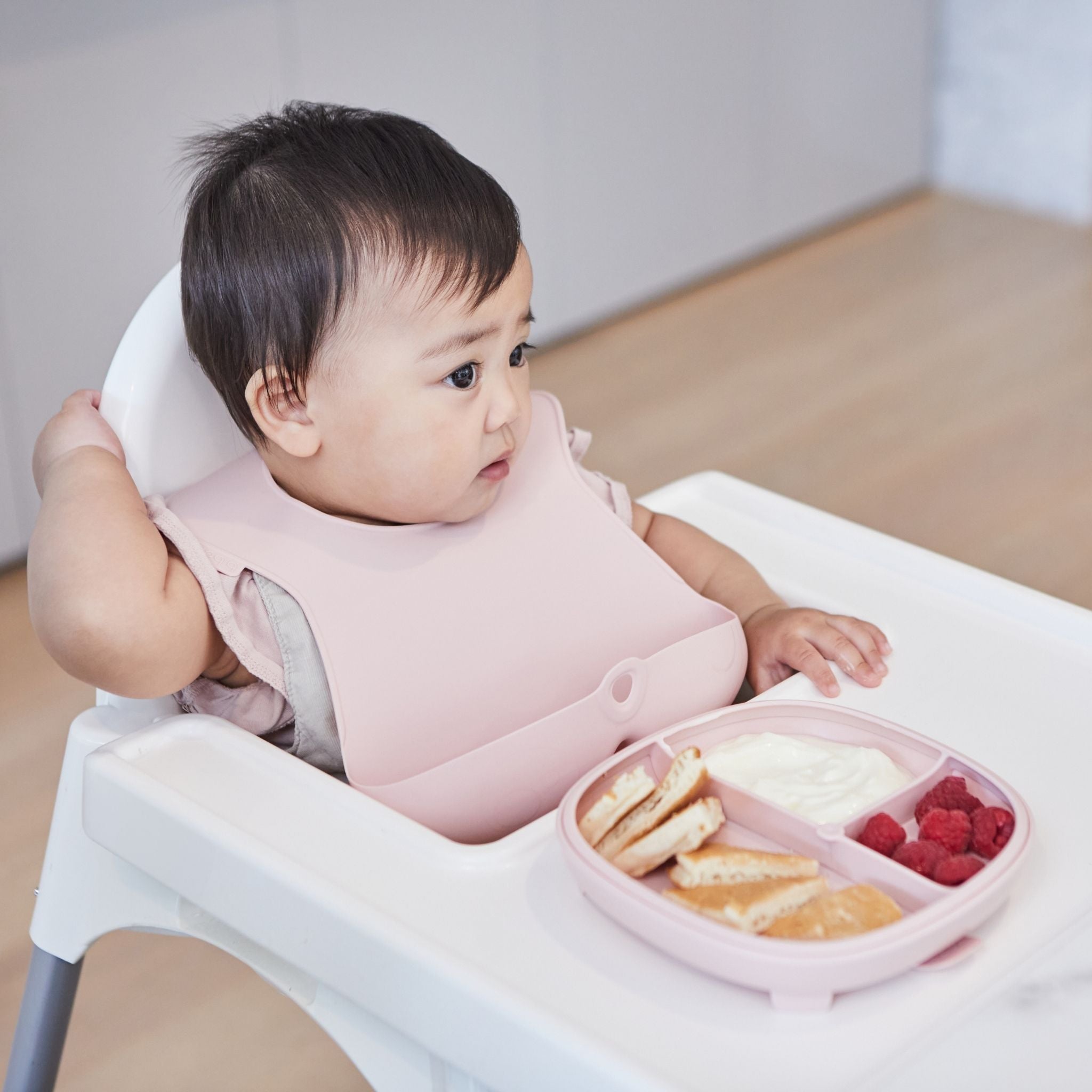 仕切りのとれる吸盤つきお食事プレートにホットケーキとヨーグルト、フルーツが盛り付けてあり、女の子がはいチェアに座っている