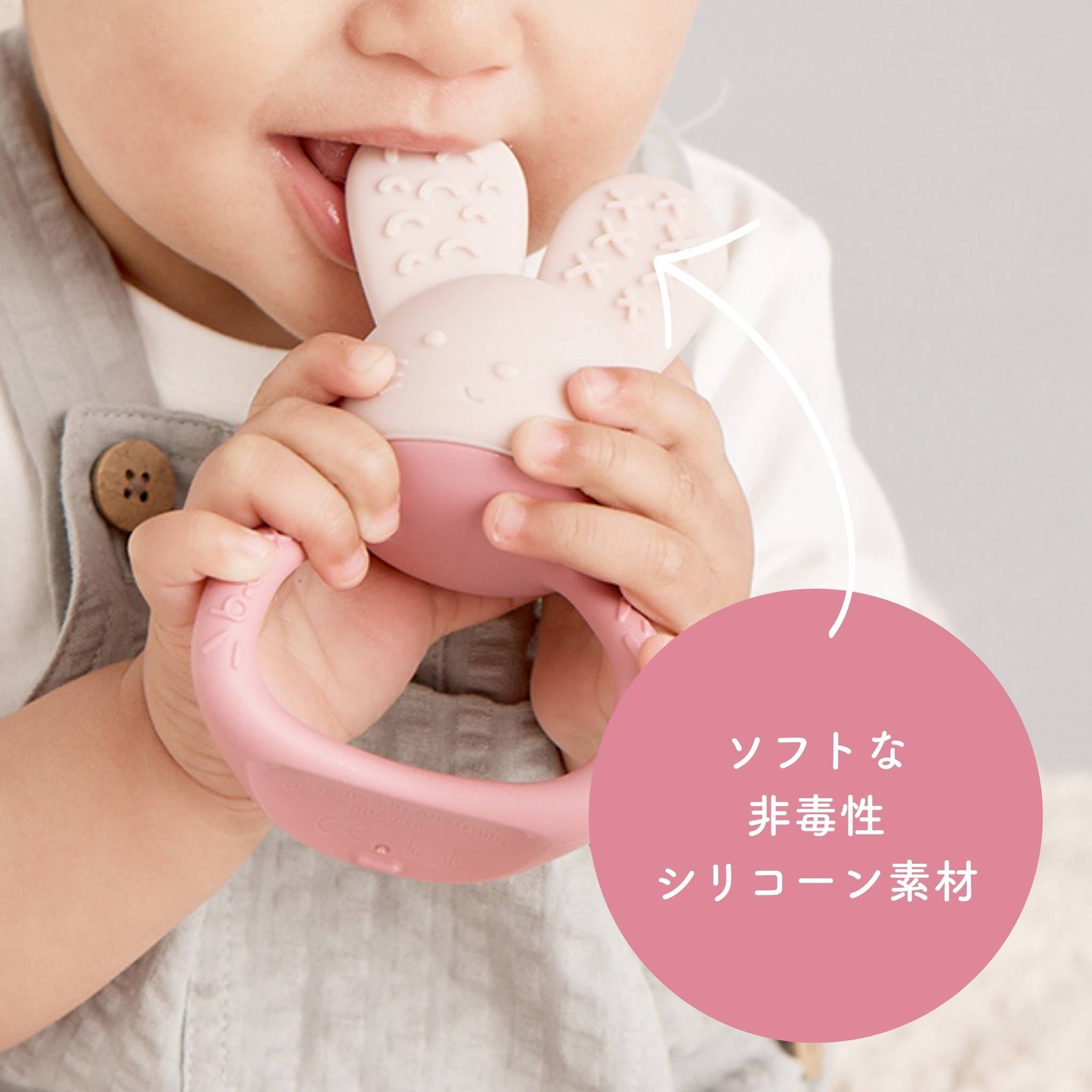 赤ちゃんが柔らかい非毒性のシリコーン素材の歯固めを噛んでいる
