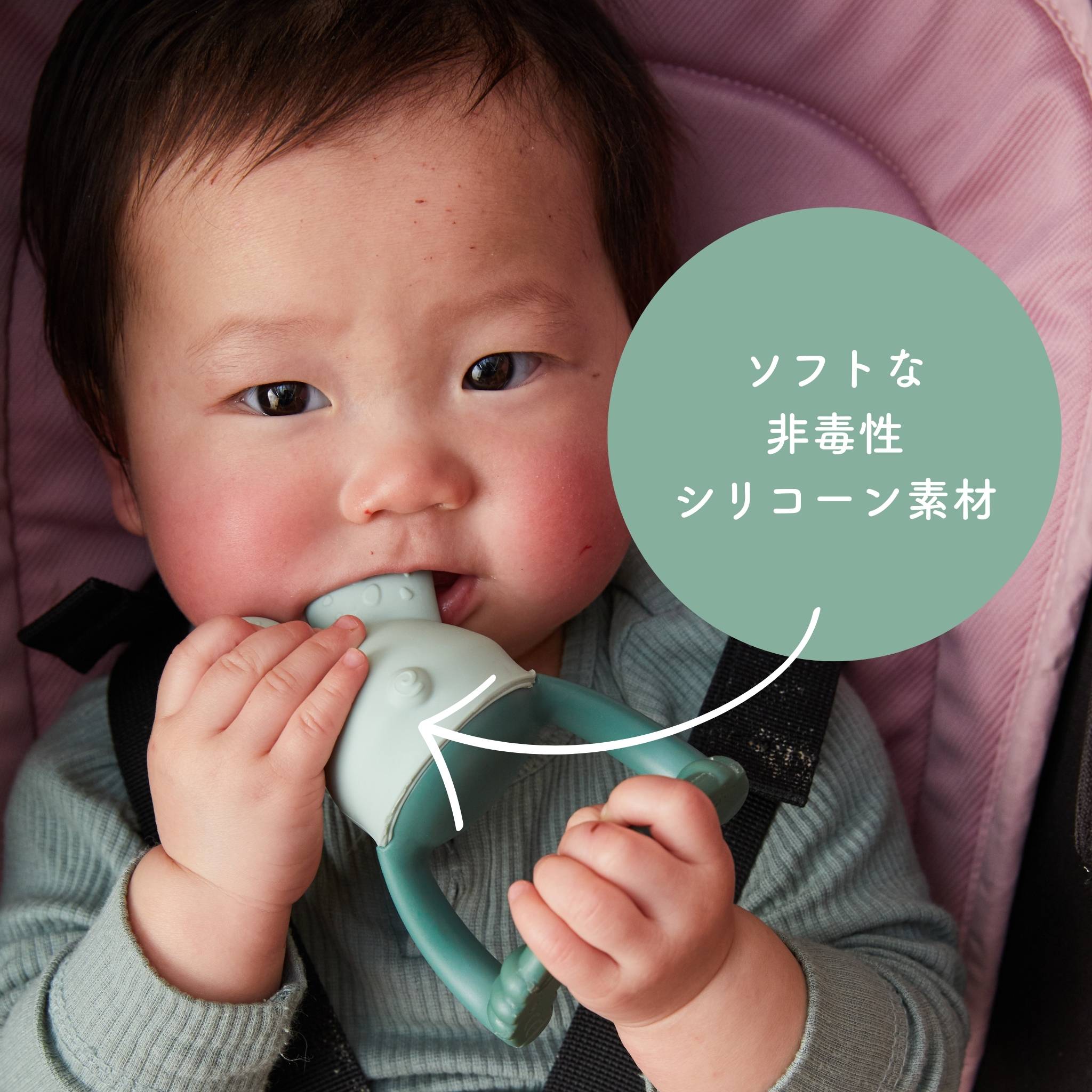 赤ちゃんが柔らかい非毒性のシリコーン素材の歯固めを噛んでいる