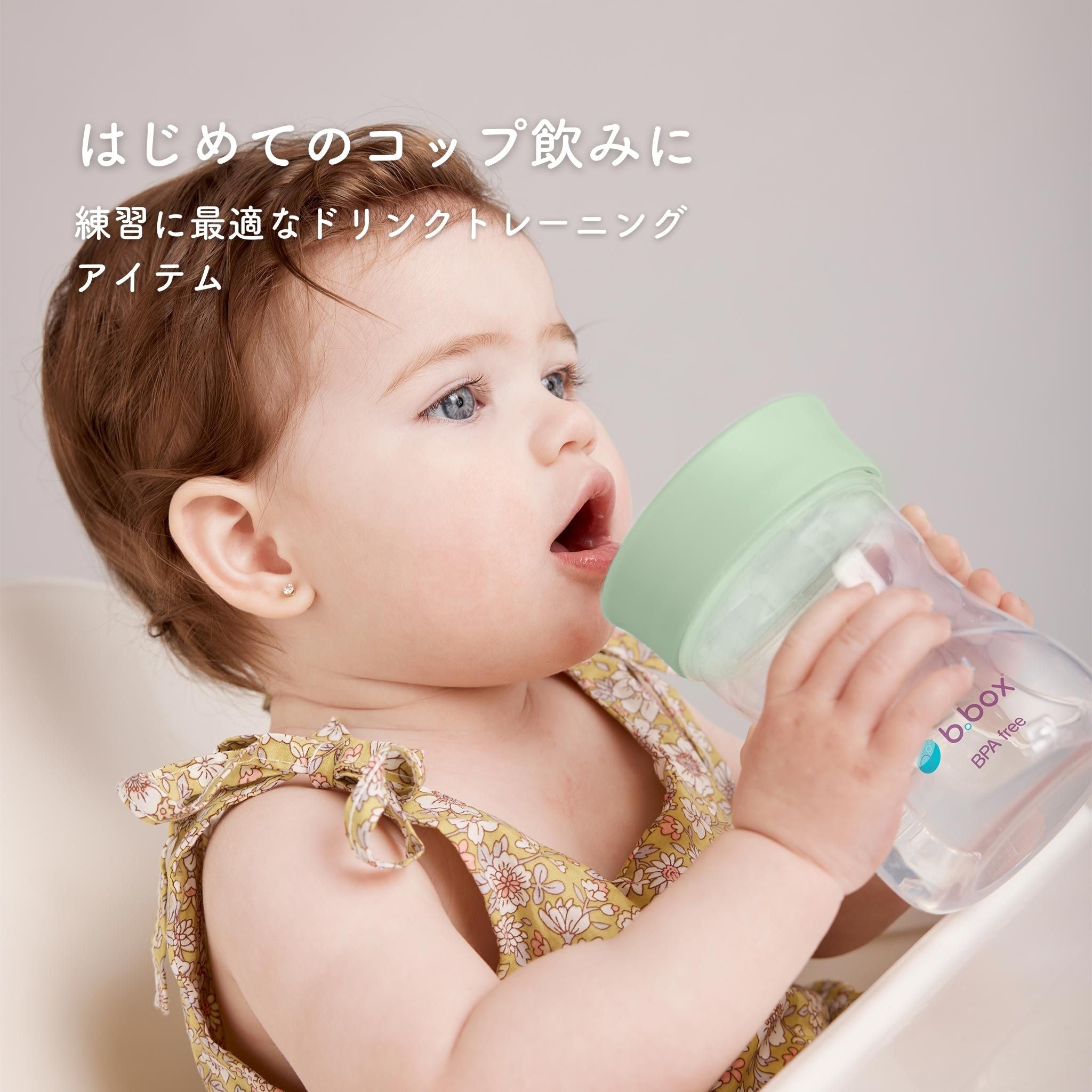 はじめてのコップ飲みに 緑色の蓋の付いたコップ飲みアイテムのを飲んでいる女の子
